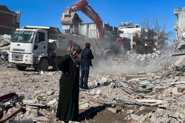 Parents of Taha Erdem, mother Zeliha Erdem (L), and father Ali Erdem stand next to the debris from the building where Taha was trapped after the earthquake of Feb. 6, in Adiyaman, Turkey, on Feb. 17, 2023. (Mehmet Mucahit Ceylan/AP Photo)
