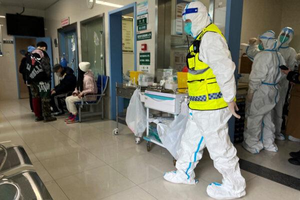 A security worker in a protective suit keeps watch as medical personnel attend to patients at the fever department of Tongji Hospital, a major facility for patients with COVID-19, in Wuhan, Hubei Province, China, on Jan. 1, 2023. (Reuters)
