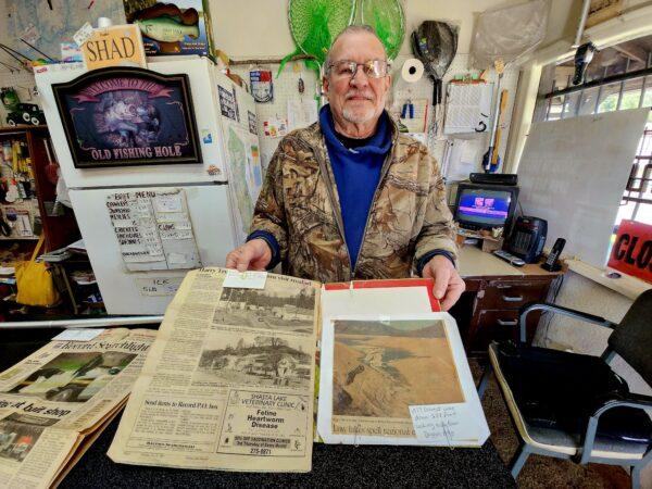 Bob Braz, owner of The Fishen Hole bait and tackle shop in the city of Shasta Lake, Calif., on Feb. 15, 2023, displays an old photograph depicting the extent of the 1976-77 drought that crippled much of Shasta Lake. (Allan Stein/The Epoch Times)