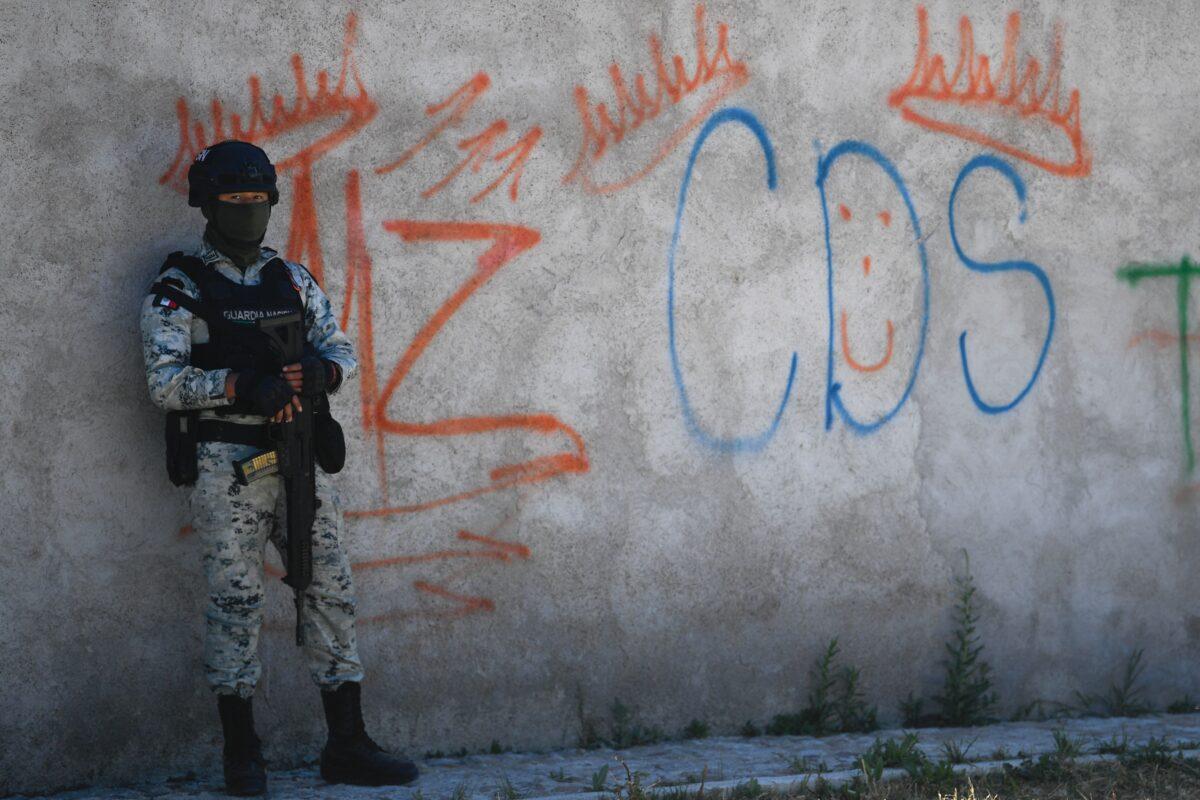 A Mexican soldier stands guard against a backdrop of graffiti linked to the criminal group "Cartel de Sinaloa" (CDS), in Palmas Altas, Zacatecas state, Mexico, on March 14, 2022. (Pedro Pardo/AFP/Getty Images)
