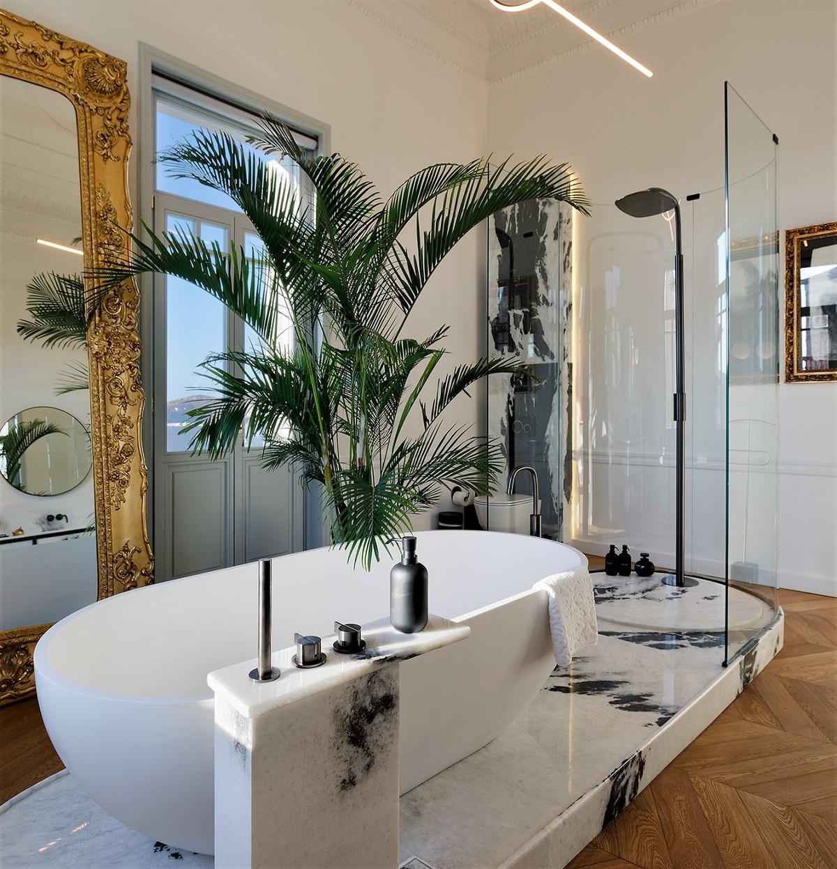 This airy bathroom features herringbone wood flooring, extensive use of gleaming marble, and a relaxing view of the nearby waters. (Courtesy of Greece Sotheby’s International Realty)