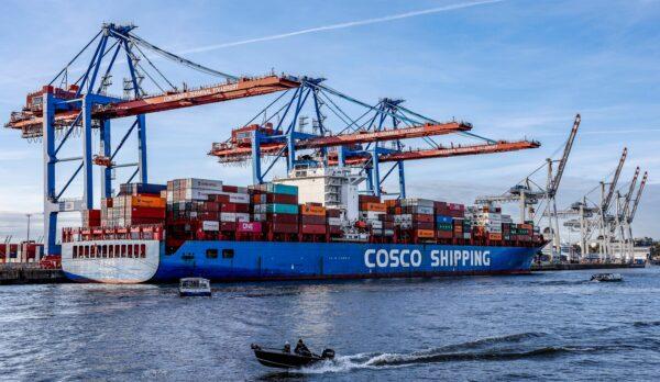Small boats pass in front of the container ship 'Xin Lian Yun Gang' of China COSCO Shipping Corporation as it is unloaded at the Tollerort Container Terminal owned by HHLA, in the harbour of Hamburg, northern Germany on October 26, 2022. (AXEL HEIMKEN/AFP via Getty Images)