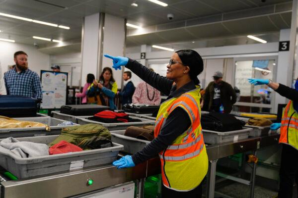 A worker points as people wait for their belongings at the Transportation Security Administration security area at the Hartsfield-Jackson Atlanta International Airport in Atlanta on Jan. 25, 2023. (Brynn Anderson/AP Photo)