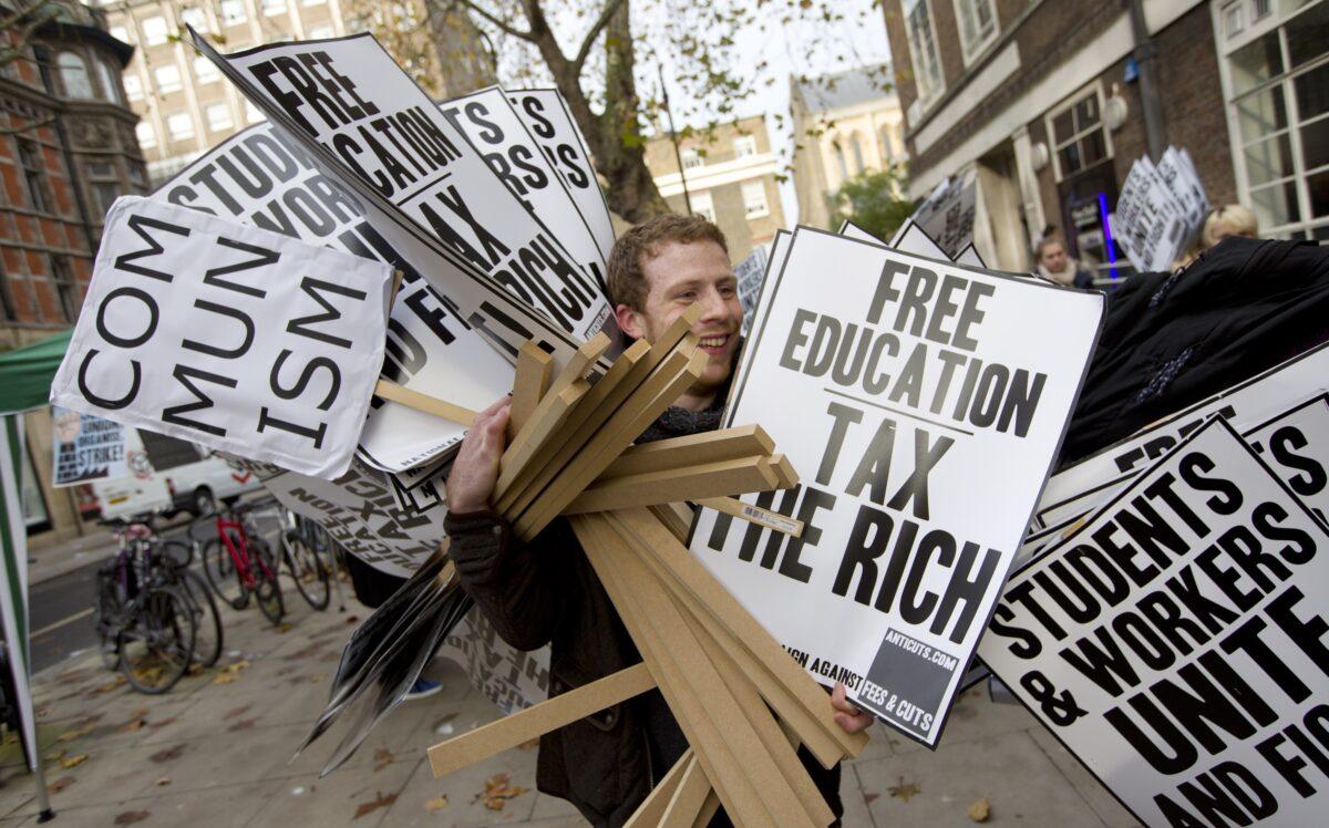 A man carries placards that read "Free education. Tax the rich" and "Communism" in a file photo. (Justin Tallis/AFP via Getty Images)