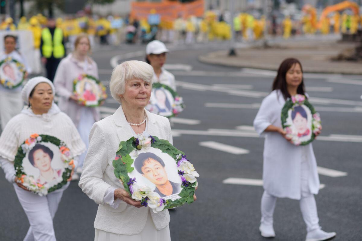 Falun Dafa practitioners carry pictures of the victims of the persecution in China during a march through the center of Warsaw, Poland, on Sept. 9, 2022. (Mihut Savu/The Epoch Times)
