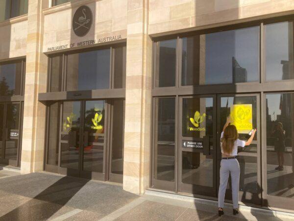 A woman was seen spraying Woodside Energy logo on the front doors of Western Australia's parliament in Perth, Australia on Feb. 21, 2022. (Courtesy of Disrupt Burrup Hub)