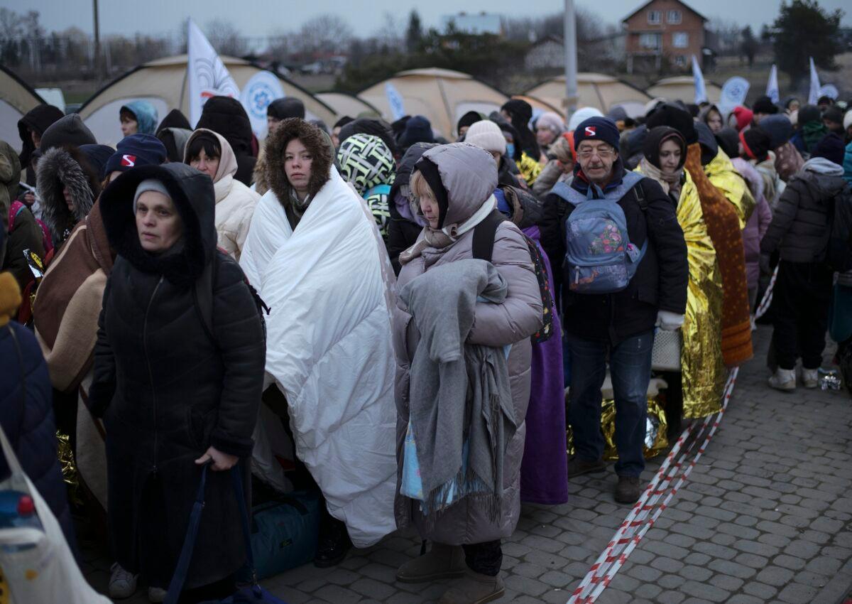 Refugees wait in a crowd for transportation after fleeing from Ukraine and arriving at the border crossing in Medyka, Poland, on March 7, 2022. (Markus Schreiber/AP Photo)