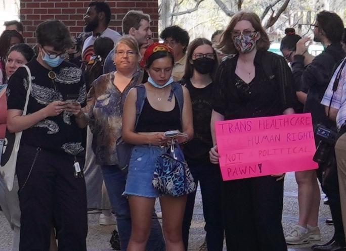 An attendee at a planned "walkout" at the University of Florida holds a sign that says "Trans Healthcare is a Human Right, Not a Political Pawn!" on the Gainesville, Fla. campus on Feb. 23, 2023. (Nanette Holt/The Epoch Times)