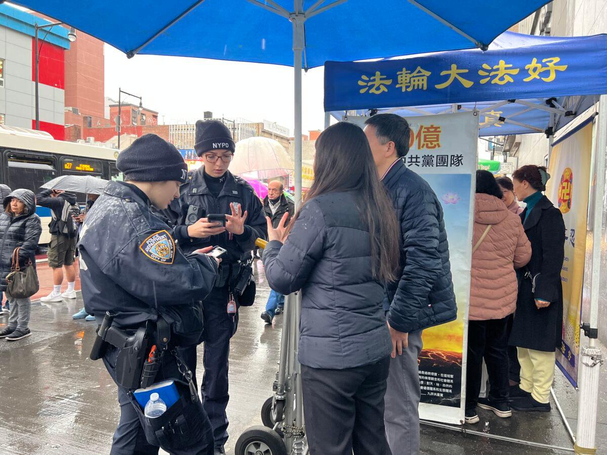 Police officers talk with Falun Gong practitioners after a man assaulted them at an information stand, in the Flushing neighborhood of Queens, N.Y., on Feb. 16, 2023. (Linda Lin/The Epoch Times)