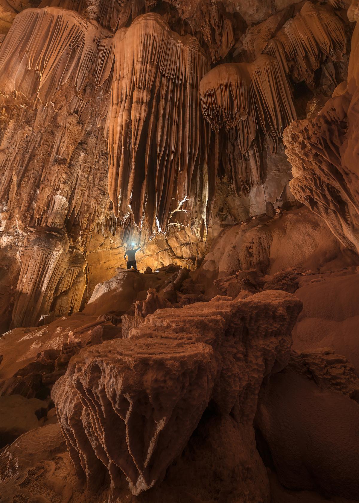 An explorer stands amid geological wonders inside Hung Thoòng Cave system. (Courtesy of Tran Linh via Jungle Boss Tours)