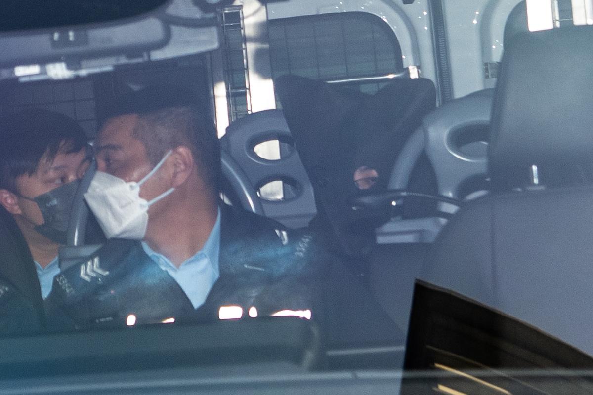 Four suspects, three men and one woman, were escorted by police to the Kowloon City Court on Feb. 27. One of the suspects, with black hoods over his head, was escorted to court by a police car. (The Epoch Times)