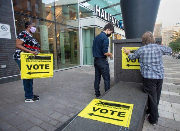 Elections Canada workers place signage at the Halifax Convention Centre as they prepare for the polls to open in the federal election in Halifax on Sept. 20, 2021. (The Canadian Press/Andrew Vaughan)