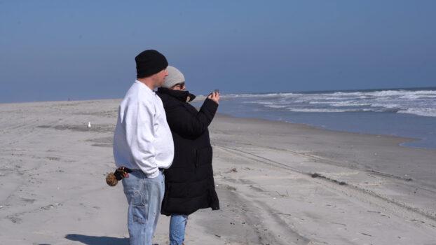 Carter Doorley’s parents watch their son surf at Brigantine Beach, N.J., on Feb. 26, 2023. (William Huang/The Epoch Times)