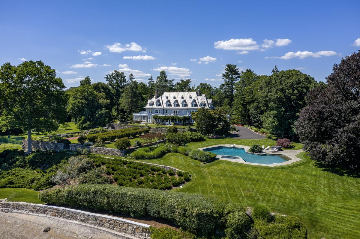 This view of the main residence from the shoreline reveals the 75-foot-long pool, manicured gardens, and surrounding swaths of nature. (Daniel Milstein for Sotheby’s International Realty)