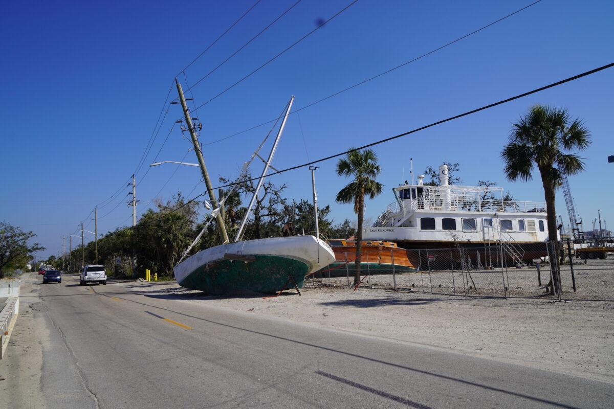 An abandoned, storm-smashed sailboat dumped outside a ship salvage yard on San Carlos Island near Ft. Myers Beach, Fla., in February 2023, five months after Hurricane Ian devastated Southwest Florida. (John Haughey/The Epoch Times)