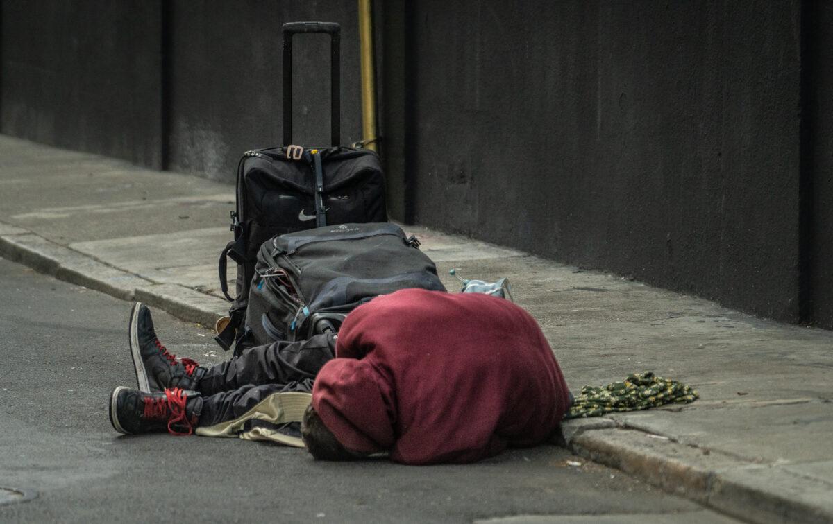 A homeless man lies passed out on the streets of the Tenderloin District of San Francisco, Calif., on Feb. 23, 2023. (John Fredricks/The Epoch Times)