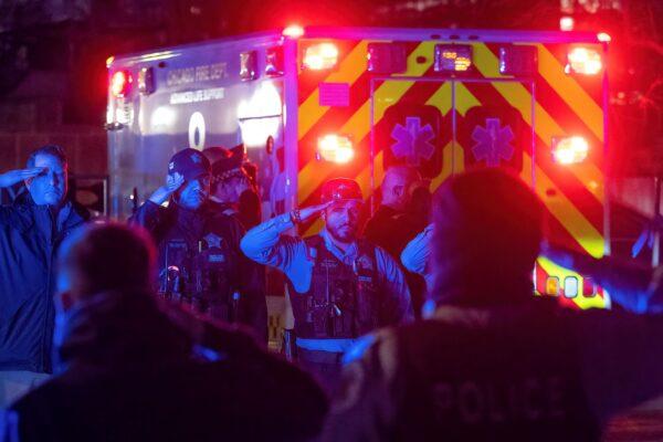 Chicago police officers and firefighters salute a procession carrying the remains of a Chicago police officer who was shot and killed as it arrives at the Cook County Medical Examiner's Office, on March 1, 2023. (Tyler Pasciak LaRiviere/Sun-Times/Chicago Sun-Times via AP)
