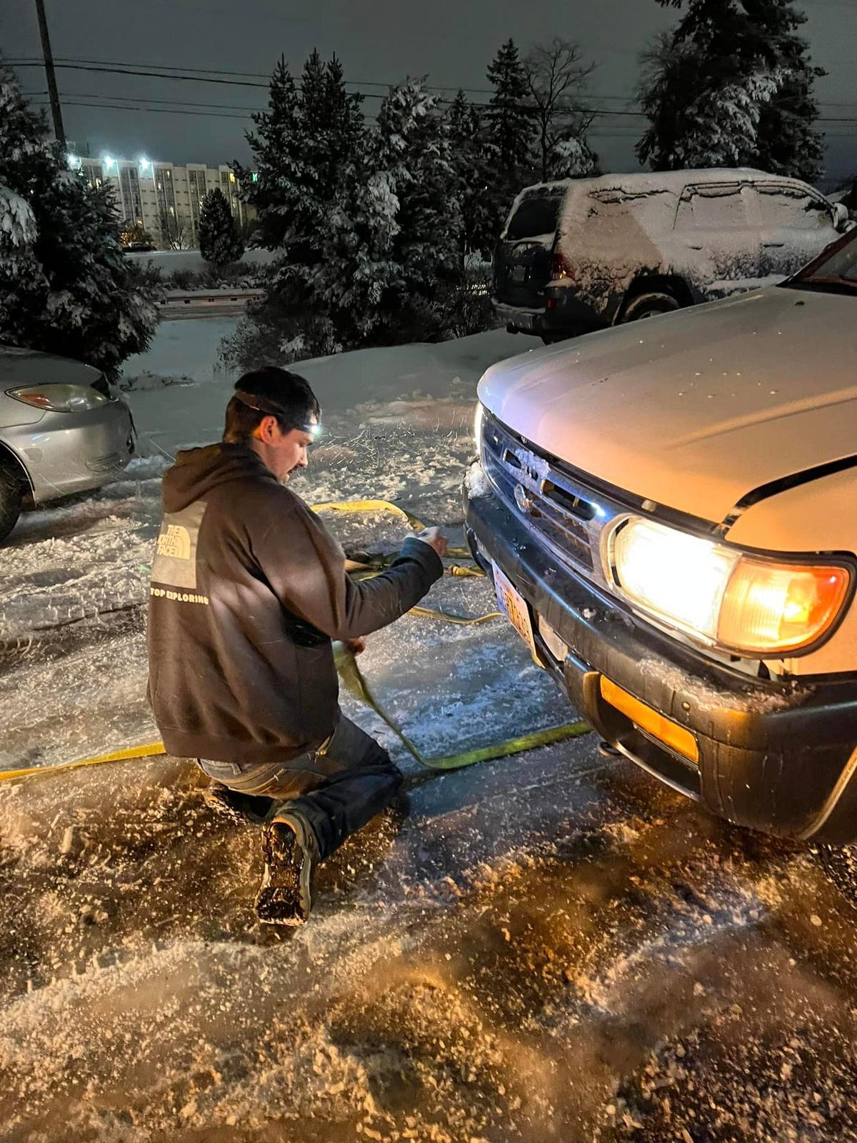 Gilbert fastening his tow straps in preparation to help haul a driver stuck on the icy road. (Courtesy of <a href="https://www.facebook.com/alec.higley">Alec Higley</a>)