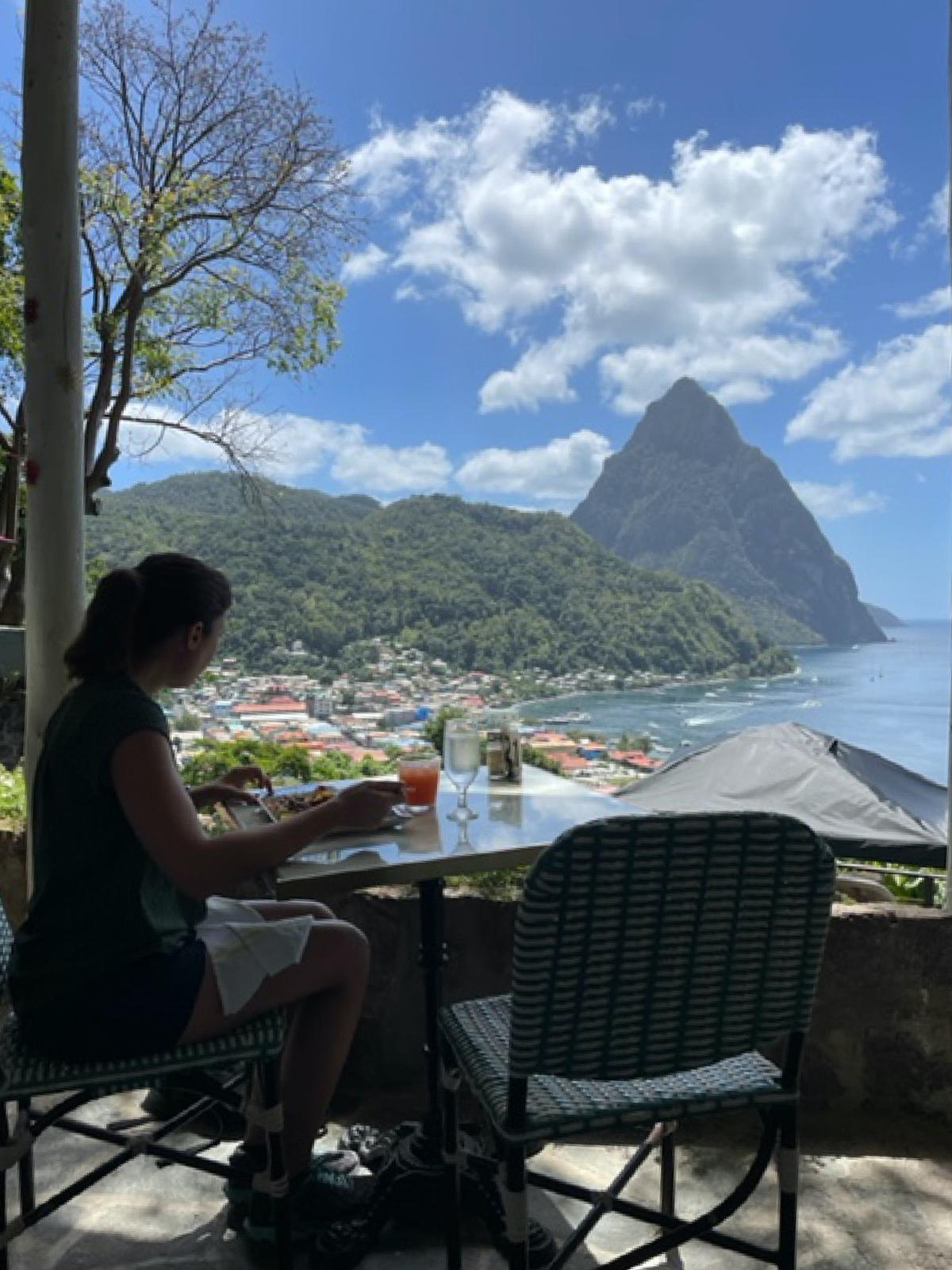 A guest enjoys open-air dining on local Creole cuisine at the Green Fig Resort with Petit Piton in the distance beyond Soufriere, St. Lucia. (Photo courtesy of Lesley Frederikson)