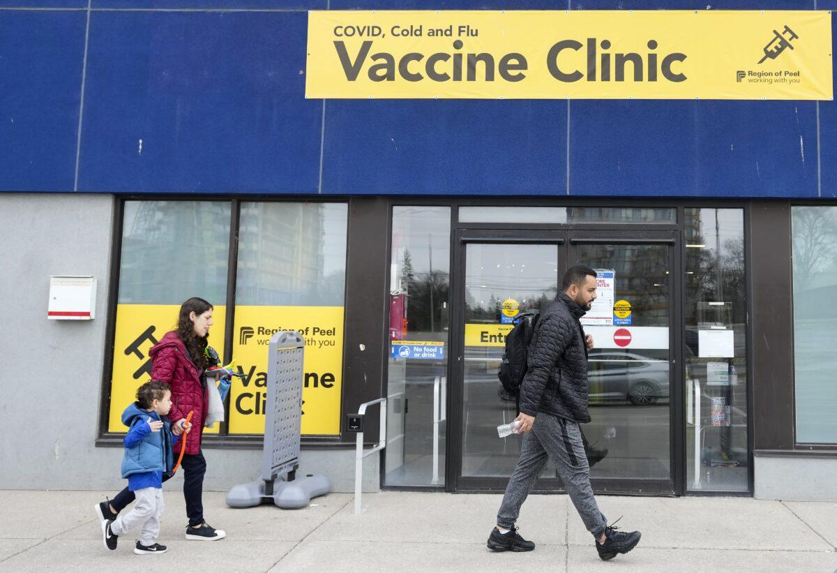 People walk past a vaccine clinic during the COVID-19 pandemic in Mississauga, Ont., on April 13, 2022. (Nathan Denette via The Canadian Press)