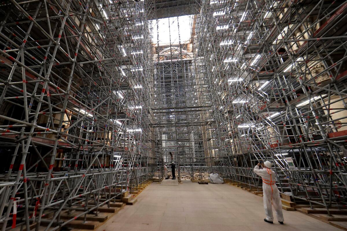 A worker takes a picture of the scaffolding's at the reconstruction site ahead a visit of the French President at the Notre-Dame de Paris Cathedral in Paris on April 15, 2022. (Ian Langsdon, Pool via AP)