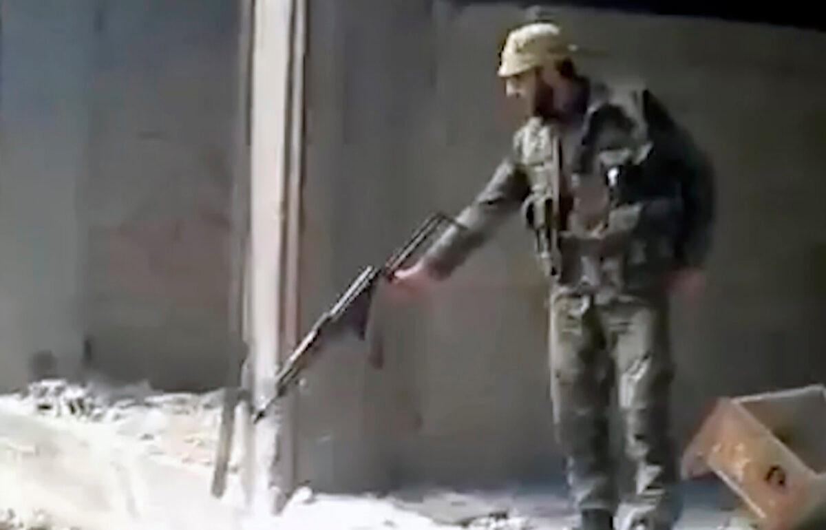 A Syrian soldier fires into a large pit full of bodies, in the Tadamon neighborhood of Damascus, Syria, in a frame grab from a 2013 video. (AP Photo)