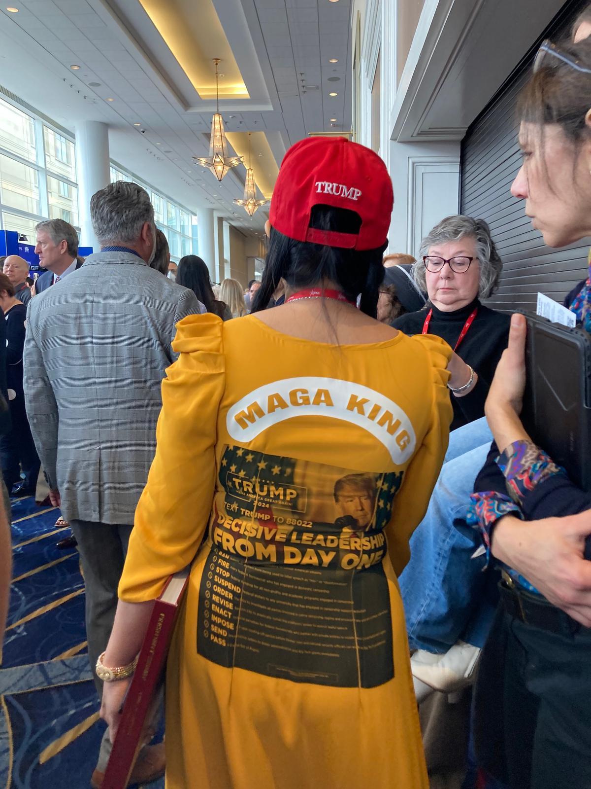 An unidentified woman makes her way through a crowded corridor at CPAC, wearing a Donald Trump-theme dress, on March 2, 2023. (Janice Hisle/The Epoch Times)