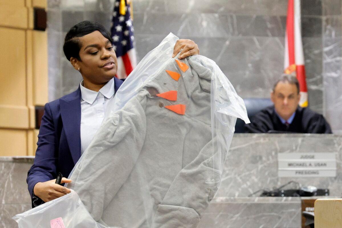 During her closing arguments in the XXXTentacion murder trial, Assistant State Attorney Pascale Achille holds up the sweatshirt worn by the victim at the time of his murder showing orange markers noting bullet holes, at the Broward County Courthouse in Fort Lauderdale, Fla., on March 7, 2023. (Amy Beth Bennett/South Florida Sun-Sentinel via AP, Pool)