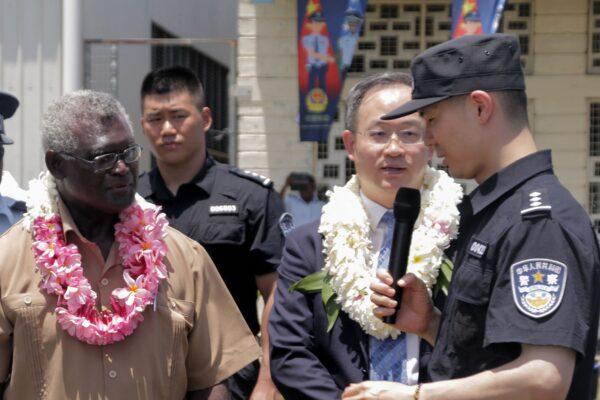 Solomon Islands Prime Minister Manasseh Sogavare (L) looks on with Li Ming (2nd R), China's ambassador to the Solomon Islands, as they listen to a Chinese police officer (R) during a ceremony in Honiara, Solomon Islands, on Nov. 4, 2022. (Gina Maka/AFP via Getty Images)