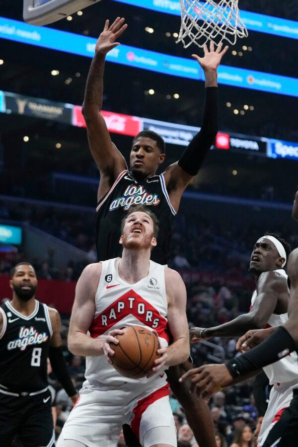 Toronto Raptors' Jakob Poeltl (19), bottom, looks to shoot under defense by Los Angeles Clippers' Paul George (13) during first half of an NBA basketball game in Los Angeles on March 8, 2023. (Jae C. Hong/AP Photo)