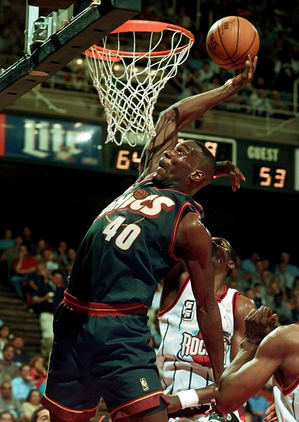 Seattle SuperSonics' Shawn Kemp (40) goes in for a dunk as Houston Rockets' Hakeem Olajuwon (34) defends during the second quarter of their NBA playoff game in Houston on May 5, 1997. (Pat Sullivan/AP Photo)