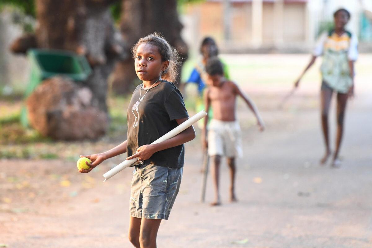 Local children play stickball on a street in Aurukun, far North Queensland, Cape York, on July 19, 2022. (AAP Image/Jono Searle)