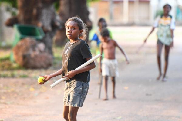 Local children play stick ball on a street in Aurukun, far North Queensland, Cape York, on July 19, 2022. (AAP Image/Jono Searle)
