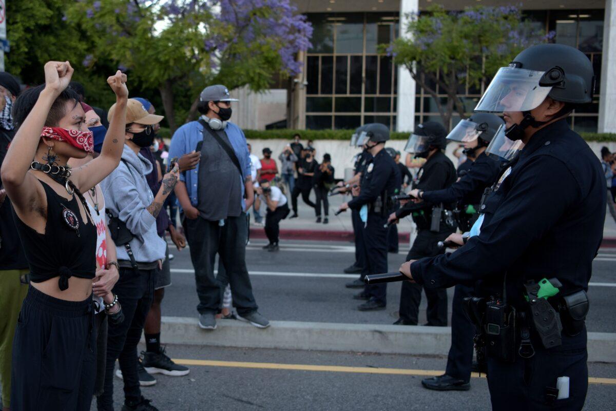 Protesters hold up their fists in front of a row of police officers as protesters gather to demonstrate after George Floyd died while in police custody, in downtown Los Angeles on May 27, 2020. (AGUSTIN PAULLIER/AFP via Getty Images)