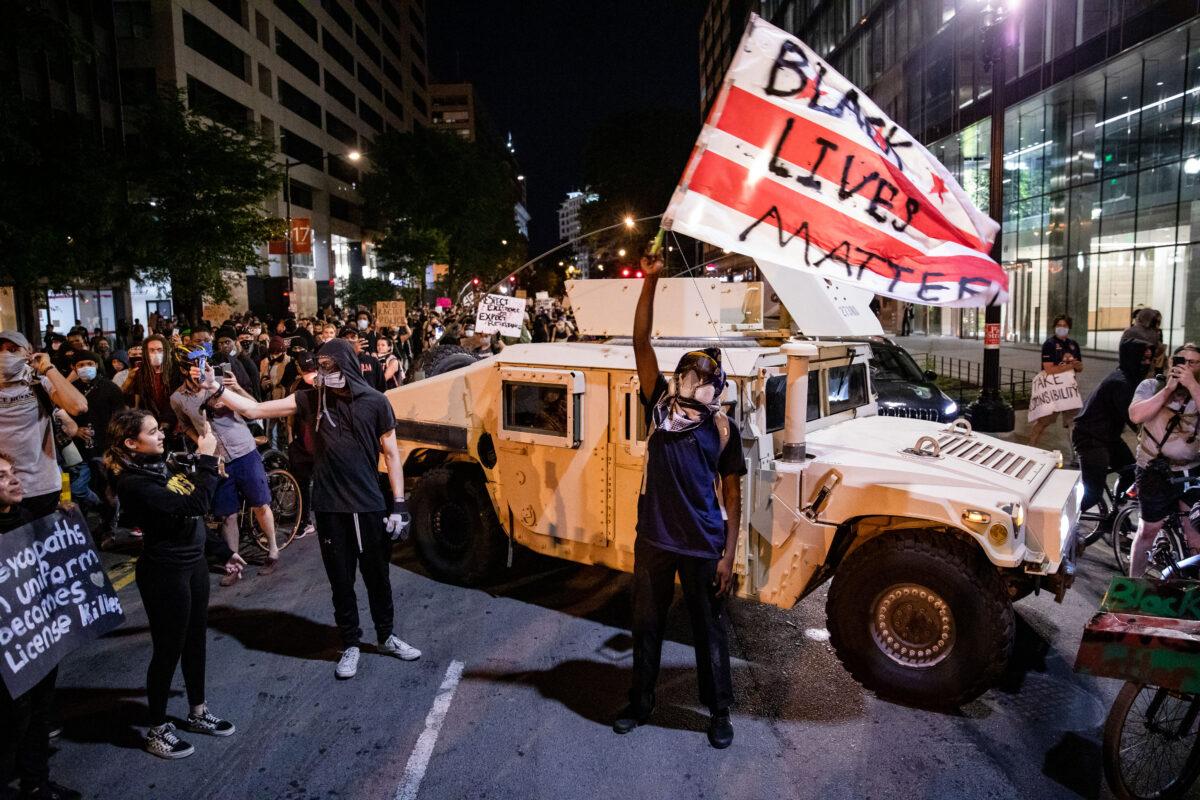 A protester waves a D.C. flag with Black Lives Matter spray painted on it as protesters march through the streets during a demonstration over the death of George Floyd, who died in police custody, in Washington on June 2, 2020. (Samuel Corum/Getty Images)