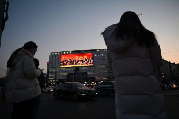 Days before the opening of the annual session of China's National Peoples Congress, people wait to cross a road near a military propaganda billboard in Beijing on March 2, 2023. (Greg Baker/AFP via Getty Images)