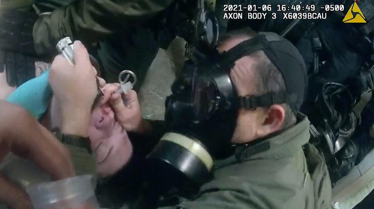 A tactical officer from U.S. Park Police inserts a breathing tube in the throat of Rosanne Boyland at the U.S. Capitol on Jan. 6, 2021. (Metropolitan Police Department/Screenshot via The Epoch Times)