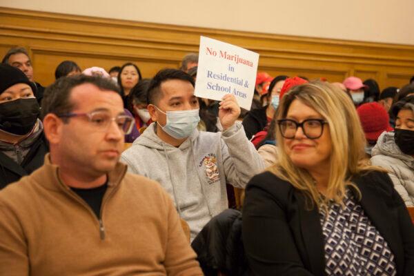 An attendee holds up a sign protesting the proposed marijuana dispensary, at a meeting of the San Francisco Planning Commission on March 9, 2023. (Lear Zhou/The Epoch Times)