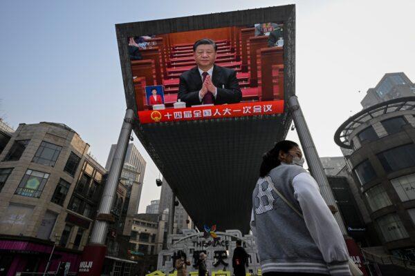 An outdoor screen shows live news coverage of Chinese leader Xi Jinping during the opening session of the National People's Congress (NPC) at the Great Hall of the People, along a street in Beijing, on March 5, 2023. (Jade Gao/AFP via Getty Images)