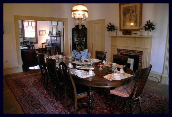 The home’s dining room, which opens to a music and game room, is furnished with an antique dining table and a mix of dining chairs, including a few ornately carved ones that have survived more than a century of use. A brass-and-glass light fixture hangs overhead, while a traditional corner armoire houses antique family porcelain. (Courtesy of Michael Johnson)