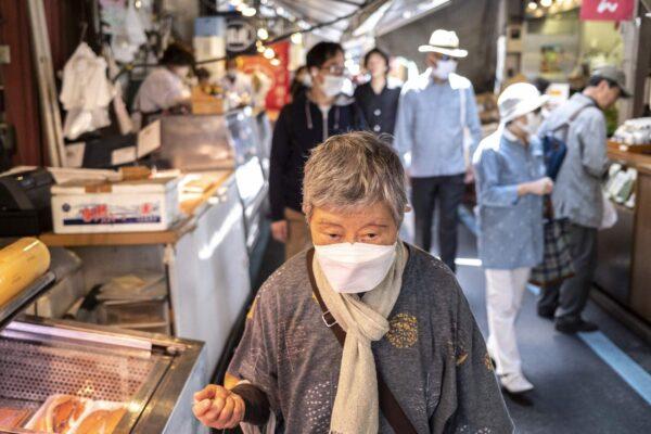 An elderly woman walks through a street market in Tokyo's Tsukiji area on April 22, 2022. (Charly Triballeau/AFP via Getty Images)