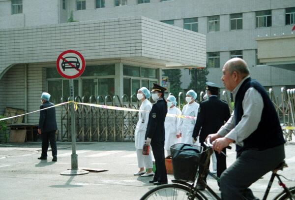 Police officers stand at the entrance of the People's hospital, which was sealed off due to an outbreak of SARS in Beijing on April 25, 2003. (Getty Images)