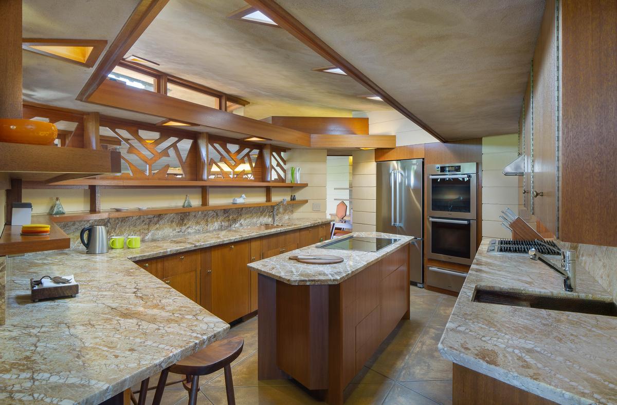 The roomy kitchen is equipped with stainless steel appliances, decorative woodwork, a large food preparation island, and oversized marble countertops. (Courtesy of Crosby Doe)