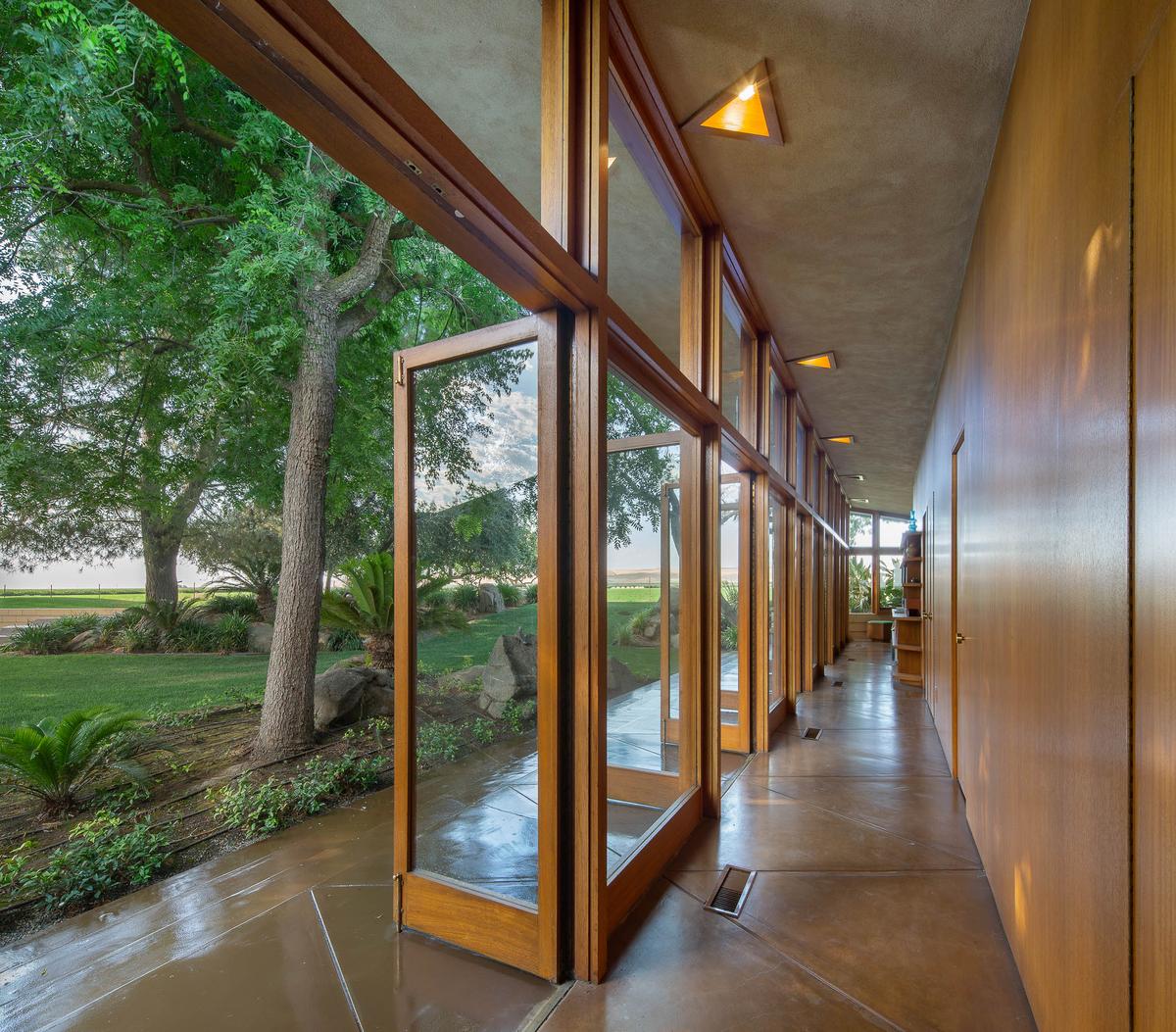 The home's wood-framed glass walls can be opened to allow in cooling breezes. Tile floors, recessed lighting, and wood paneling provide a warm ambiance. (Courtesy of Crosby Doe)