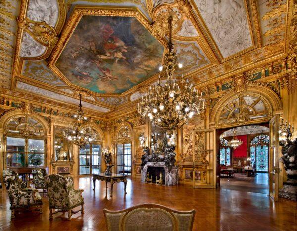 The Grand Salon (also called the Gold Room) served as a ballroom and was recognized as “one of the grandest ballrooms ever to be built in Newport.” The Gold Room features gold gilt paneling over wooden walls carved to represent scenes from classical mythology, inspired by the Apollo Gallery at the Louvre. (Courtesy of The Preservation Society of Newport County)