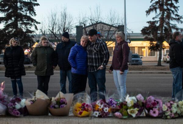 The family of Constable Brett Ryan look over flowers laid at a vigil for Ryan and fellow Constable Travis Jordan who were shot and killed while on duty, in Edmonton on March 17, 2023. (Jason Franson/The Canadian Press)