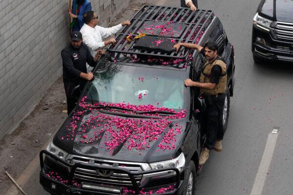 Security personnel climb on a vehicle carrying former Prime Minister Imran Khan as it moves toward Islamabad at a road in Lahore, Pakistan, on March 18, 2023. (K.M. Chaudary/AP Photo)