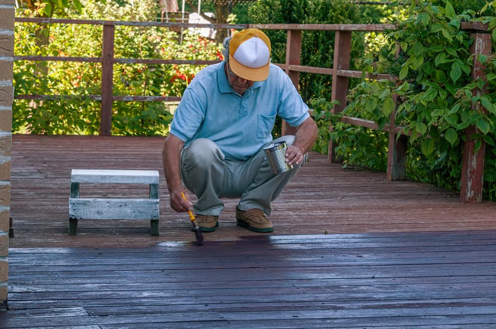 Deck maintenance includes inspecting the wood for damage, stripping it of its existing stain, and reapplying stain or sealer.(LesPalenik/Shutterstock)