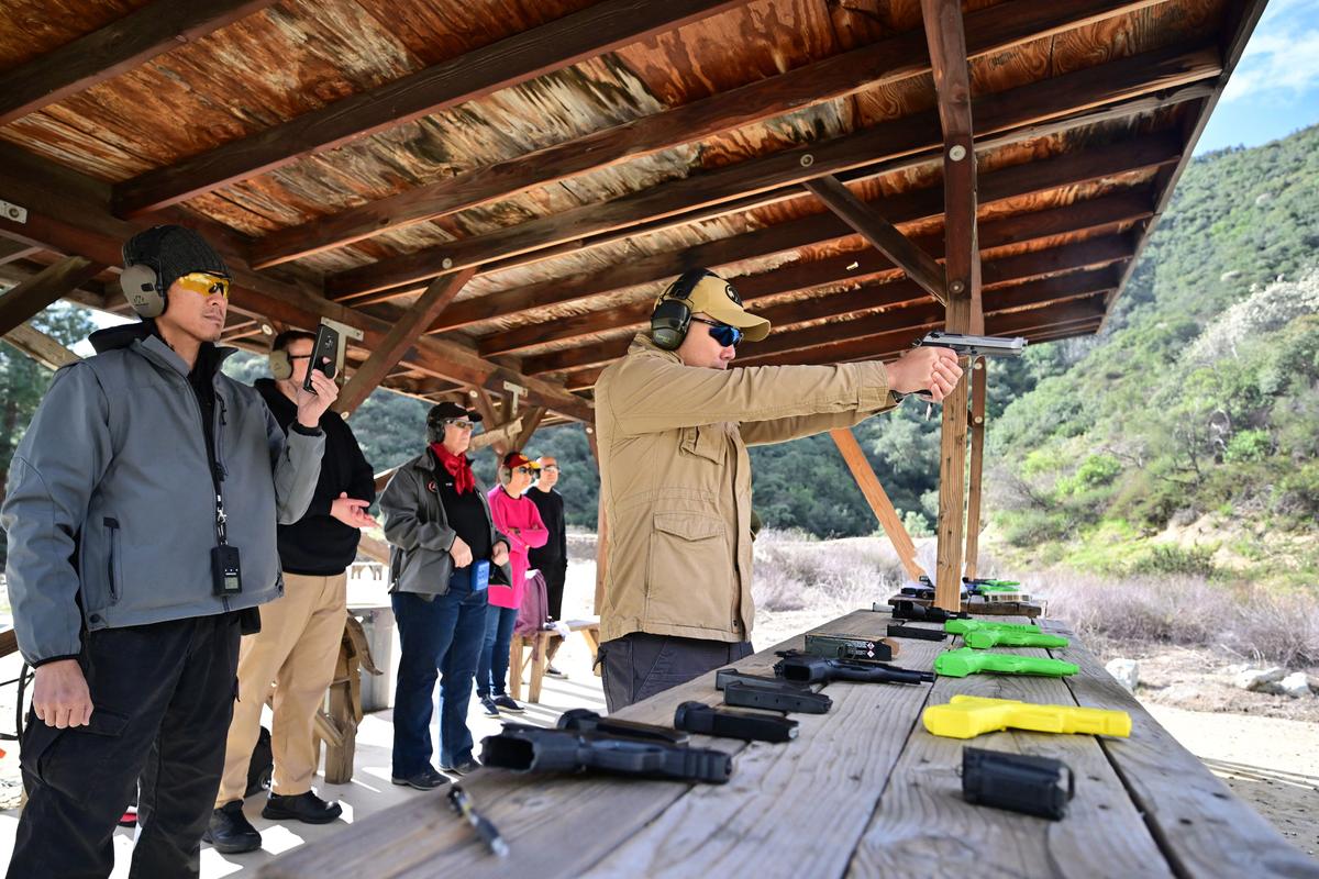 Gun instructor Tom Nguyen (L) watches as Kelly Siu fires a pistol during a Defensive Pistol Class at Burro Canyon Shooting Park in Azusa, Calif., on Feb. 12, 2023. (Frederic J. Brown/AFP via Getty Images)