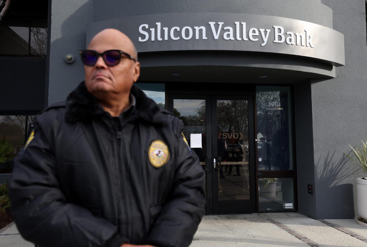 A security guard at the failed Silicon Valley Bank monitors a line of people outside its office in Santa Clara, Calif., on March 13, 2023. (Justin Sullivan/Getty Images)